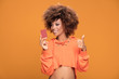© neonshot - Young afro girl holding credit card on yellow background.