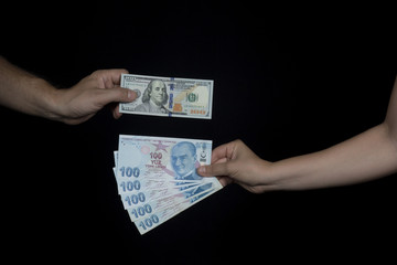 Hands of adult people showing how much exchange rate between one hundred American Dollar and Turkish Lira after general election in the Turkey. Close up taken,on his black background.