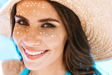 Wall Mural - beautiful brunette woman in straw hat smiling at camera