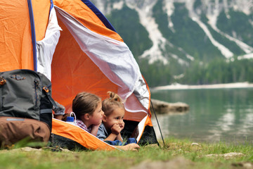 Portrait of two smiling girls (kids) in a curtain with the lake in the backround. Concept: Family, holiday, happiness