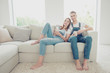 © deagreez - Young attractive cute couple wearing overall sitting home on sofa bearfoot, drinking coffee