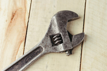 Old adjustable wrench on a wooden background.