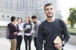 © Blue Jean Images - Cheerful male abroad student on campus with his friends in background