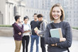 © Blue Jean Images - Cheerful female abroad student on campus with her friends in background
