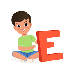 Wall Mural - Cute boy sitting with crossed legs and holding big letter E. Cartoon character of little kid. Fun educational game. Flat vector design