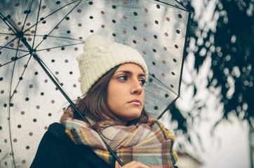 Closeup of young beautiful girl under a umbrella in an autumn rainy day