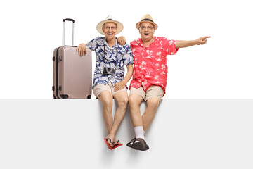 Canvas Print - Two elderly tourists sitting on a panel with one of them pointing