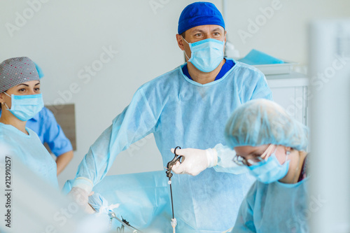 Fotomural Surgeons team preforming operation uterus removal in hospital operating theater, male surgeon operating patient working with surgical laparoscopy instruments