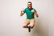 Leinwandbild Motiv Cheerful bearded hipster man with sunglasses jump over white background and showing thumbs up