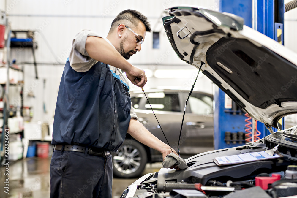 Handsome mechanic job in uniform working on car