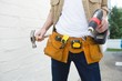 © Wavebreak Media - Male carpenter with tool belt holding hammer and drill machine