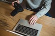 © Wavebreak Media - Man using laptop while holding digital camera