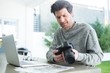 © Wavebreak Media - Man using laptop and holding digital camera