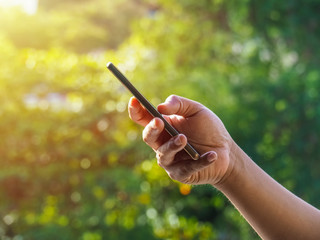 Close up of a man's hand using mobile smart phone outside on sunny summer day