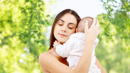 family and motherhood concept - happy smiling young mother with little baby over green natural backg