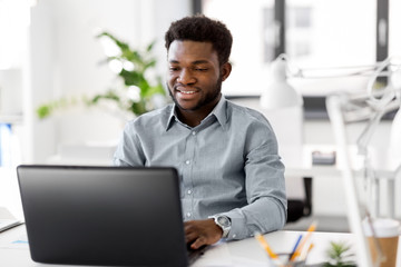 business, people and technology concept - african american businessman with laptop computer working 