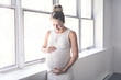 © Louis-Photo - pregnant woman with belly at home close to a window