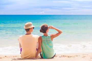 Wall Mural - back view of couple sitting on a tropical beach on Maldives