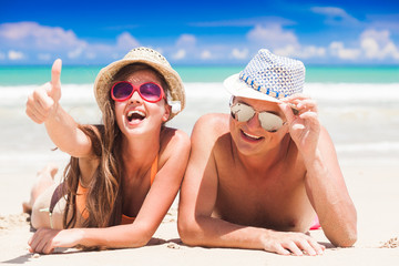 Wall Mural - happy young couple lying and having fun on a tropical beach