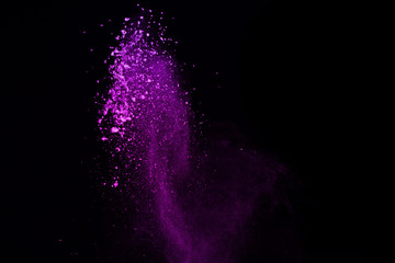 Freeze motion of purple color powder exploding on black background.