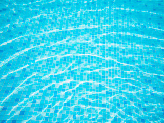 Wall Mural - swimming pool top view background, sun reflection on the blue clear water ripples of swimming pool with mosaic bottom.