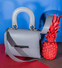 Fashion grey bag with red pineapple on the red and dark blue background