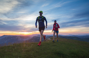 A couple trail running in the hills during sunset. Shallow D.O.F.