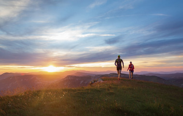 Wall Mural - Two athletes trail running in the hills during a beautiful sunset. Shallow D.O.F.