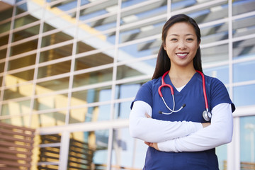 Smiling Asian female healthcare worker with arms crossed