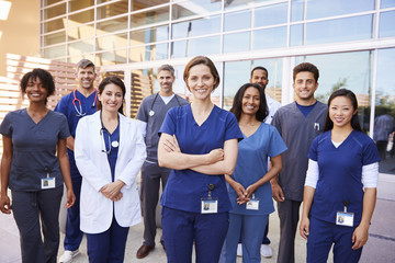 Team of healthcare workers with ID badges outside hospital