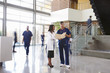 © Monkey Business - Two healthcare workers talk in the lobby of a busy hospital