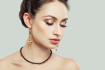 Wall Mural - Perfect Girl with Makeup and Jewelry against White Wall. Gold Earrings and Necklace