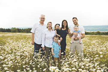 Family with grandparent spending time with little child during the sunset.