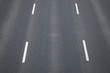 Fragment trzypasmowej drogi asfaltowej bez samochodów z namalowanymi białą farbą pasami