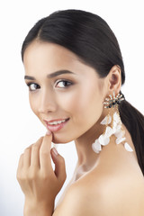 Wall Mural - Beauty portrait of a beautiful smiling brunette girl model with bare shoulders and brown eyes wearing earrings imitation jewelry isolated on white background.