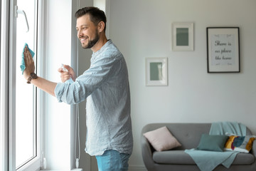 Canvas Print - Man in casual clothes washing window glass at home