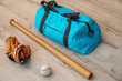 Sports bag, baseball ball and bat on wooden floor