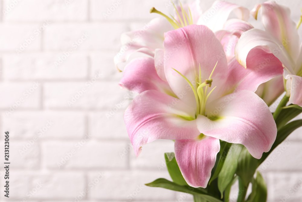 Beautiful blooming lily flowers on brick wall background - obrazy, fototapety, plakaty 