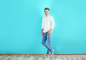 Wall Mural - Young man in stylish jeans near color wall