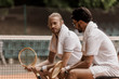 © LIGHTFIELD STUDIOS - retro styled tennis players sitting on chairs with towels and rackets at tennis court