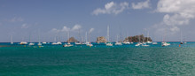 Multiple Sailboats Anchored In The Caribbean With Small Islands In Background