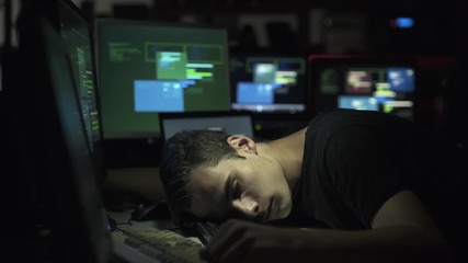 Computer developer and hacker sleeping on his desk at night