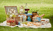 Blanket with picnic food set on green grass