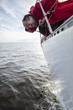 A man in a red jacket suffers from seasickness while walking on a yacht.