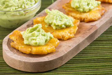 Sticker - Patacon fried pieces of crushed green banana. Guacamole. On the wooden table (toston, tachino)