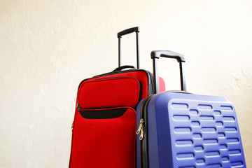 Wall Mural - Red textile suitcase & blue hard shell luggage, extended telescopic handle up, white decorative texture wall background. Couples retreat trip concept. Packed traveling baggages. Close up, copy space.