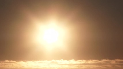 Wall Mural - On a clear sky day, bright and warm sun sets below cloud horizon, day to night time lapse.