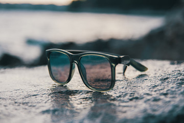 Male sunglasses on the rock near the sea