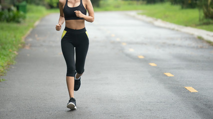Wall Mural - Young fitness sport woman running on the road in the morning, Selective focus