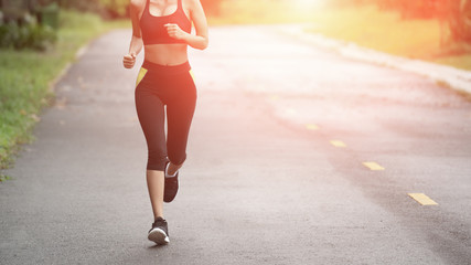Wall Mural - Young fitness sport woman running on the road in the morning, Sun light flare , Selective focus